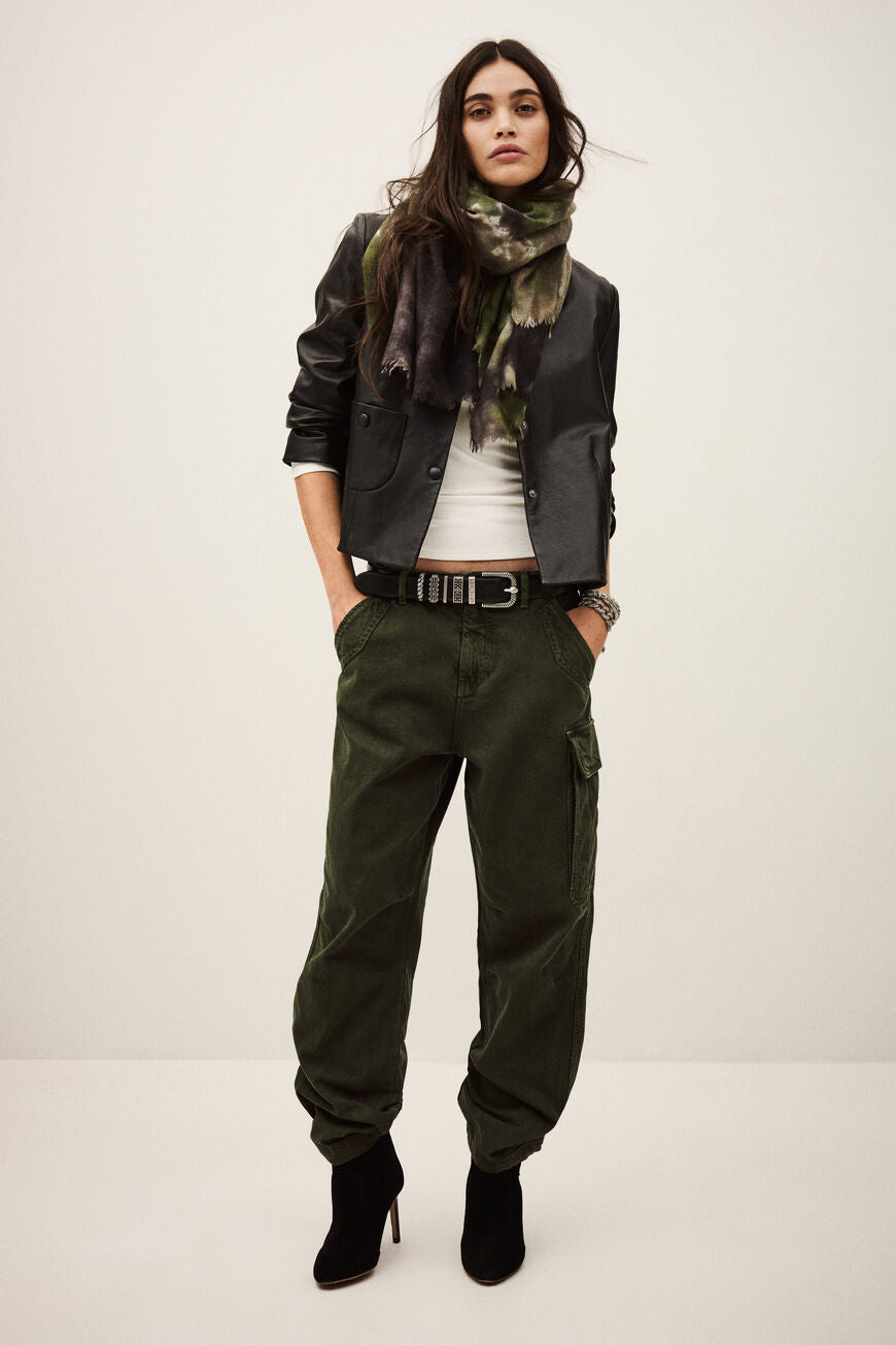 Woman wearing green cargo pants with a plain background