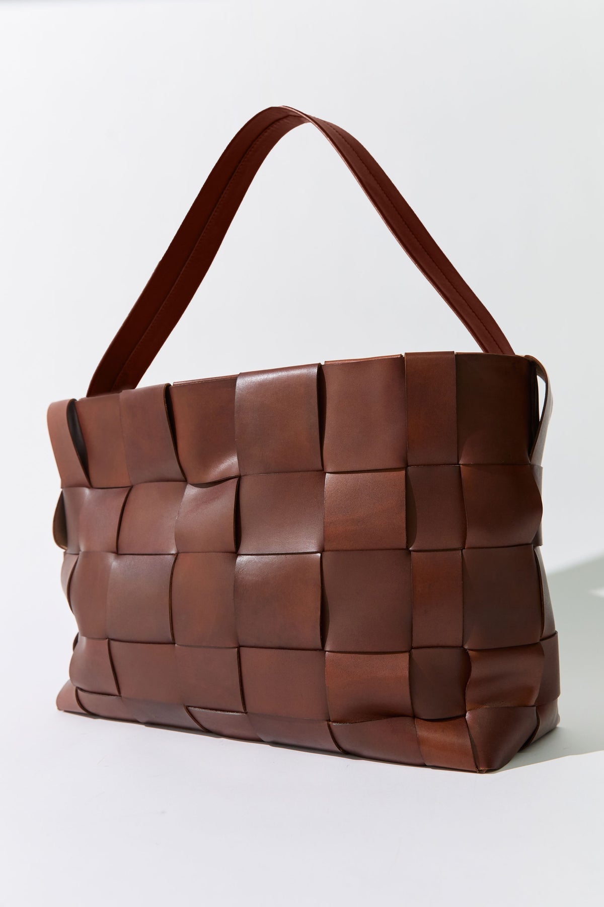 Brown woven leather handbag on a white background